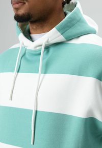 Turquoise en wit gestreepte hoodie met een capuchon met trekkoord, voorzien van een zachte stoftextuur en een ontspannen pasvorm.