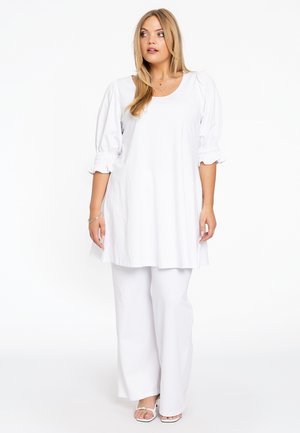 Witte tuniek met pofmouwen en een ronde halslijn, gecombineerd met witte wijde broekspijpen. Glad materiaal, comfortabele pasvorm en minimale details.