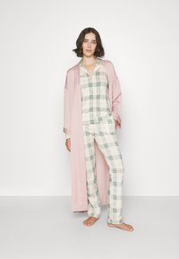 Loungewear-Set mit einem hellrosa Bademantel, einem karierten Hemd und einer passenden Hose aus weichem, atmungsaktivem Material. Komfortorientiertes Design.