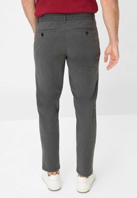 Pantalons gris ajustés avec une finition texturée, dotés de poches arrière doubles, d'une coupe slim et de ourlets finis. Associés à des baskets blanches.