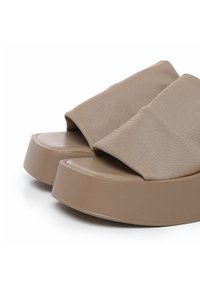 Beige platform sandaler med en bred, tekstureret stofrem og en glat, rund sål for ekstra højde og komfort.