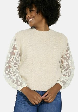 Light beige knit sweater with cable design and sheer floral lace puff sleeves. Sweater features a round neckline and ribbed hem.