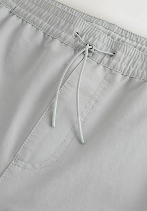 Shorts griși deschiși cu talie elastică, sistem de închidere cu șnur și detaliu cu buzunar cusut în față. Textură de țesătură moale.