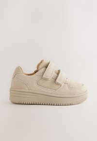 Baskets en daim beige avec deux sangles en velcro, un bout arrondi et une semelle en caoutchouc texturée arborant un motif rainuré.