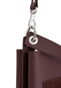 Burgundowa skórzana torba z metalowymi elementami w kolorze srebrnym, paskiem z zatrzaskiem w kształcie homara oraz ogólną gładką teksturą z zamszowym wykończeniem z przodu.