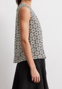 Hihaton pusero kuviollisesta kankaasta, jossa on geometrinen mustavalkoinen kuvio, pehmeä rakenne ja rento istuvuus.