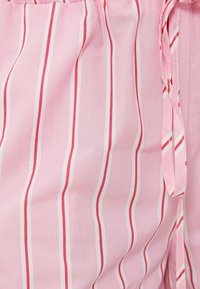 Lys pink stof med lodrette striber i mørkere pink og hvid. Har en snoretræk detalje i taljen, blød tekstur og fløjlsagtig design.