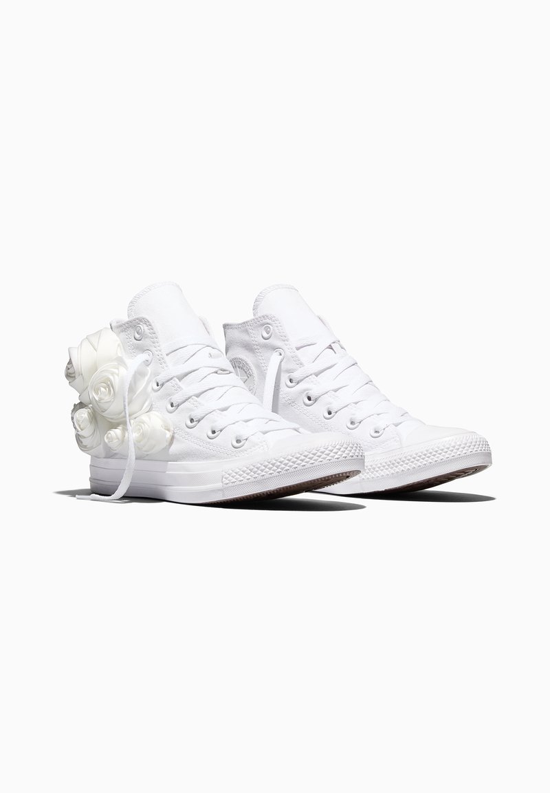 Een paar witte hoge canvas sneakers met witte veters, versierd met witte 3D roosvormige versieringen aan de buitenkant.