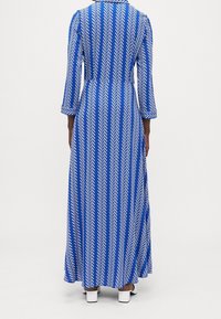 Długa niebieska sukienka w białą skośną krateczkę, z długimi rękawami i kołnierzykiem, wykonana z gładkiego materiału, sięgająca kostek.