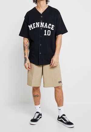 Camisa negra de botones con "MENNACE" y "10" impresos en blanco. Combinada con pantalones cortos beige y zapatillas negras. Ajuste casual con mangas cortas.