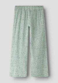 Pantalon large vert clair avec motif tacheté noir et taille élastique, présenté sur un fond uni.