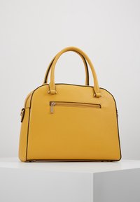 Żółta torebka o strukturalnym kształcie, wykonana z teksturowanej skóry, z górnym uchwytem, czarnymi wykończeniami i kieszenią zapinaną na zamek z przodu.