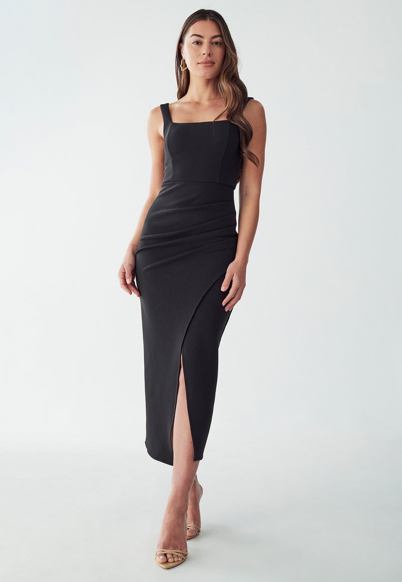 Black, form-fitting midi dress, featuring a square neckline, wide straps, and a side slit. Textured fabric and subtle shaping details.