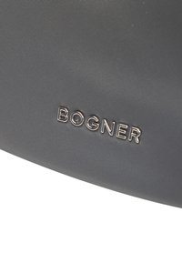 Harmaa kangaspussi, jossa on teksturoitu pinta ja metallinen "BOGNER"-logotehoste, korostaen minimalistista muotoilua ja kestävyyttä.