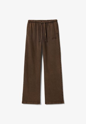 Bruine joggingbroek van zacht stof, met een elastische tailleband, trekkoord en een logodetail op de dij. Recht model.