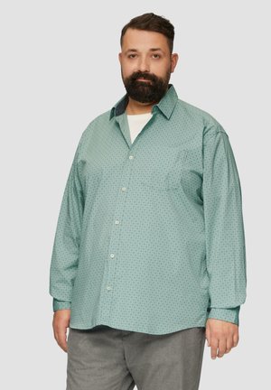 Lange mouw lichtgroene shirt met een klein geometrisch patroon, button-down kraag en één borstzak. Draag over een wit T-shirt.