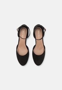 Black suede ankle strap shoes with a rounded toe, flat heel, and a smooth beige interior. Features a gold-tone metal buckle.