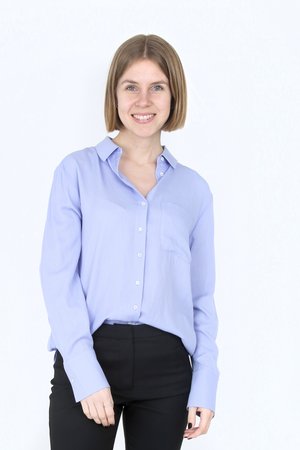 Light blue button-up shirt with long sleeves, a pocket on the left, and silver buttons, paired with black fitted pants.