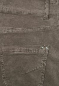 Brune corduroy bukser med en baglomme med to metalnitter, lodret syning og en blød, struktureret overflade.