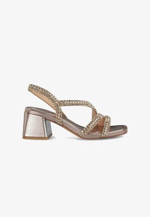 Sandalias de tacón tipo slingback en bronce metálico, con tiras cruzadas decoradas con cristales y un tacón cuadrado grueso.