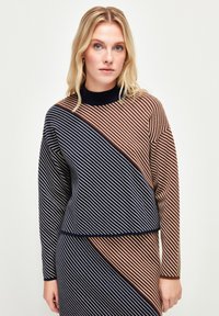 Sweter dzianinowy w diagonalne paski w kolorach granatowym, brązowym i kremowym, z wysokim dekoltem i luźnym krojem. Miękka tekstura, długie rękawy.