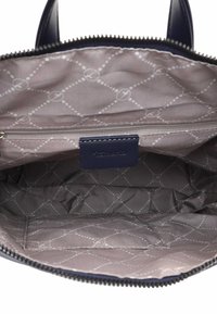 Interno della borsa navy con fodera grigia trapuntata, logo in rilievo e tasca con zip. Presenta un motivo a diamante e una texture liscia.