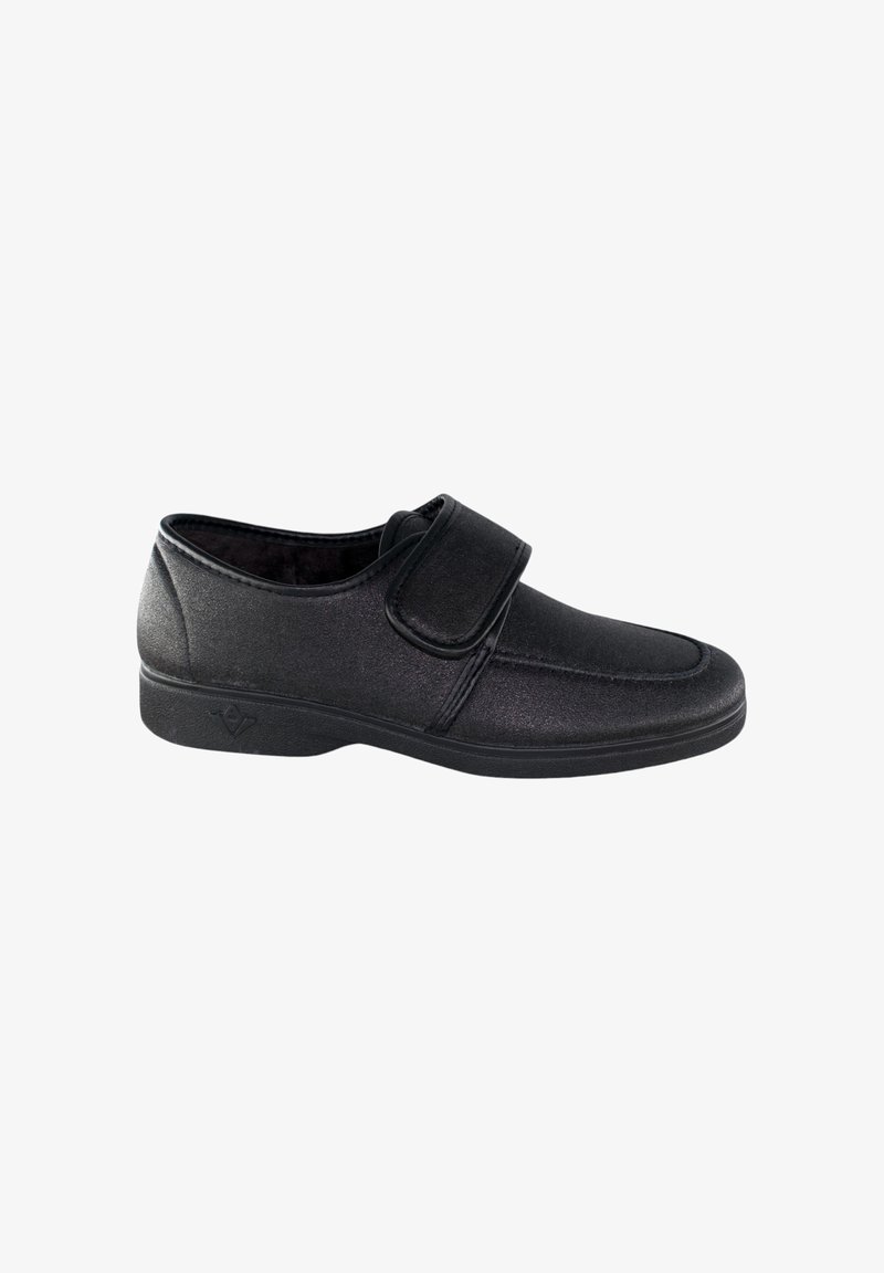 Zapato negro con tira de velcro, textura suave, punta redonda y suela de goma baja. Diseño minimalista adecuado para uso casual.