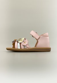 Ροζ σανδάλι για νήπιο με ανθικά διακοσμητικά, ρυθμιζόμενο λουράκι στον αστράγαλο και επίπεδη καφέ σόλα, πλαϊνή όψη σε ουδέτερο φόντο.