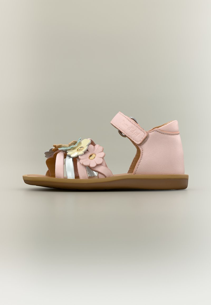 Ροζ σανδάλι για νήπιο με ανθικά διακοσμητικά, ρυθμιζόμενο λουράκι στον αστράγαλο και επίπεδη καφέ σόλα, πλαϊνή όψη σε ουδέτερο φόντο.