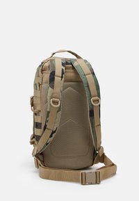 Plecak w wzór camo z siatkowym panelem tylnym, beżowymi wyściełanymi paskami i regulowanymi klamrami bocznymi. Wykonany z trwałego materiału o uporządkowanej konstrukcji.