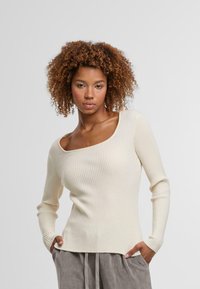 Gestreifter, langärmeliger Oberteil in Off-White, mit quadratischem Ausschnitt und strukturiertem Stoff. Gerader Saum mit dezenten Seitenschlitzen. Lässige Passform.