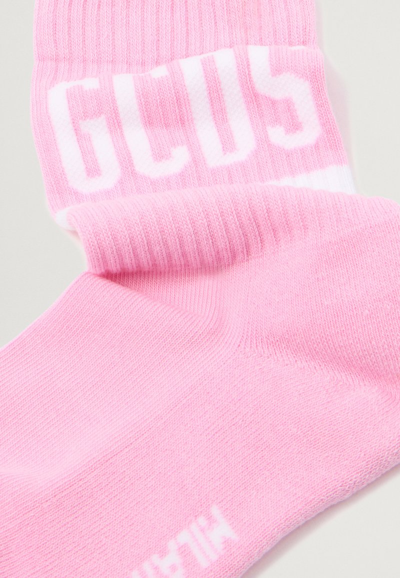 Chaussettes en coton rose à la cheville avec une texture côtelée, arborant des inscriptions blanches audacieuses sur le rebord et une finition lisse sur l'ensemble.