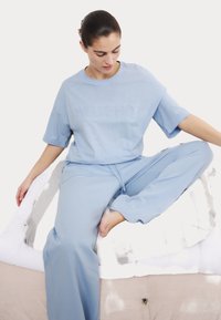 Conjunto de loungewear azul claro que incluye una camiseta de manga corta con la palabra "WEEKEND" en relieve y pantalones a juego con un ajuste relajado y cintura con cordón.