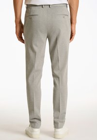 Pantalones ajustados de color gris claro con bolsillos traseros, diseño elegante, textura suave y corte cónico, combinados con zapatillas blancas.