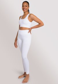 Top sportivo bianco a costine e leggings a vita alta con dettagli testurizzati. Tessuto morbido, design aderente e costruzione senza cuciture migliorano il comfort.