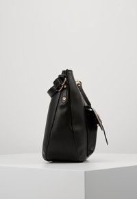 Borsa a tracolla in pelle nera dalla forma strutturata, con chiusura a zip, tracolla regolabile e dettagli in metallo dorato.