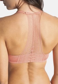 Bralette rose clair avec un dos en dentelle, présentant un motif au crochet et des bretelles fines. Tissu lisse avec une texture douce.