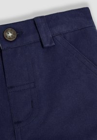 Pantalons bleu marine en tissu durable, dotés d'une fermeture à bouton métallique, de passants de ceinture et de surpiqûres visibles.