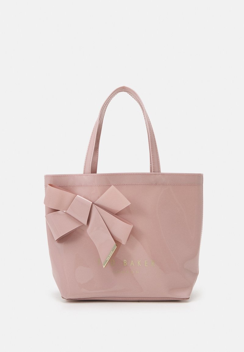 Petit sac à main rose brillant avec deux anses et un grand nœud décoratif sur le devant à gauche.