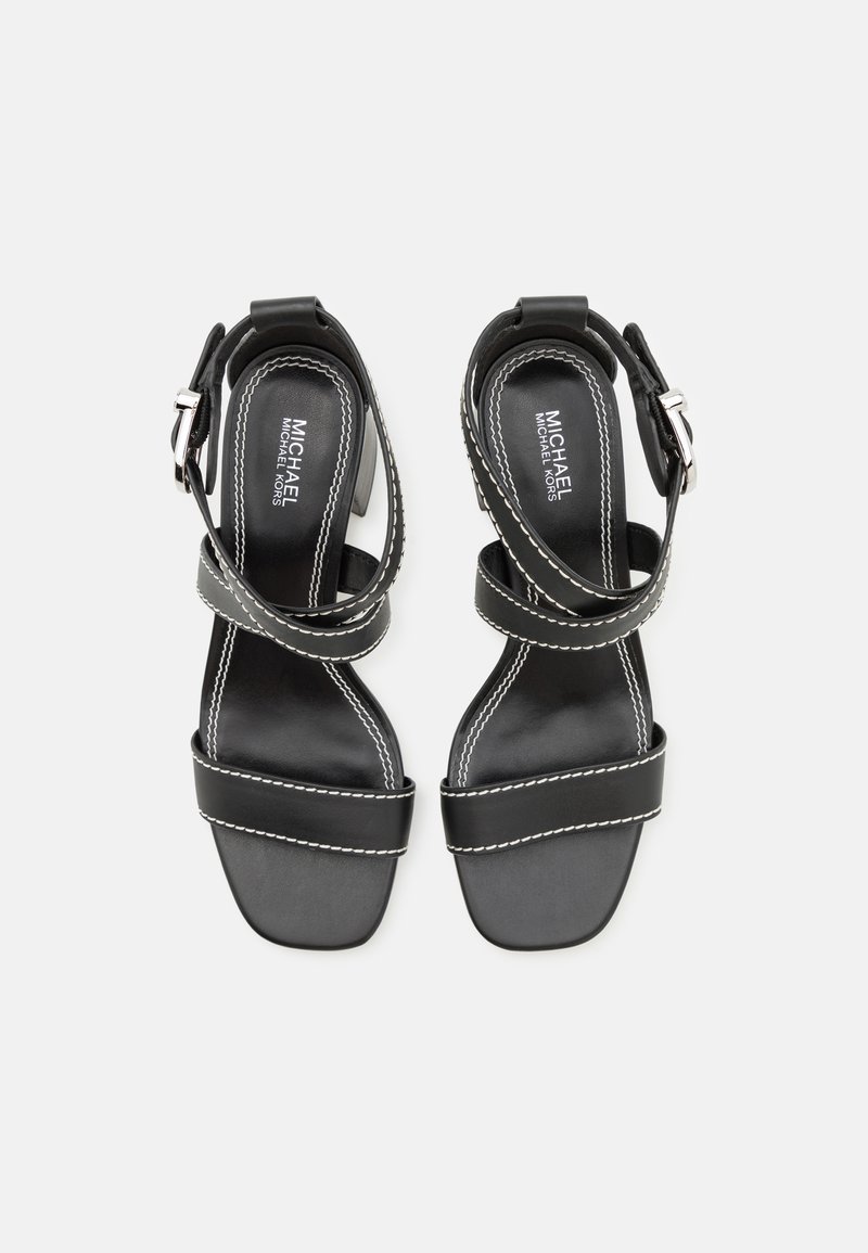 Czarne skórzane sandały z kwadratowym noskiem, paskiem na kostkę i srebrną klamrą. Białe przeszycia podkreślają paski. Teksturowana powierzchnia.
