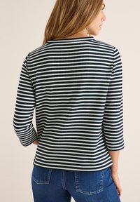 Maglietta a righe blu navy e bianca a maniche lunghe con scollatura rotonda e maniche a tre quarti, realizzata in un tessuto testurizzato.