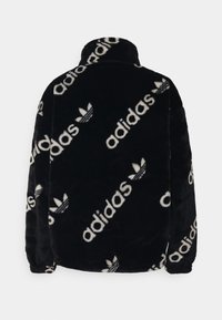 Černá fleecová bunda s vysokým límcem zdobená opakujícím se bílým logem Adidas a motivem trojlístku. Měkká textura s dlouhými rukávy.