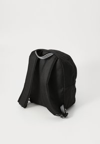 Zwarte stoffen rugzak met een padded structuur, twee verstelbare schouderbanden, een handvat aan de bovenkant en witte gestreepte accenten op de schouderbanden.