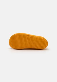 Semelle de chaussure en caoutchouc de couleur orange vif avec une surface texturée et antidérapante. Présente un embout arrondi et un design plat et large.