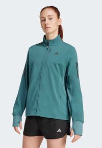 Teal jacket with a high collar and zip closure. Features black accents and thumbholes. Worn over black shorts with a subtle logo.