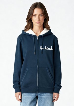 Marineblaue Zip-Up-Hoodie mit weißem Fleece-Innenfutter, "be kind"-Textdesign, vorderen Taschen und gerippten Bündchen. Weicher, gemütlicher Stoff mit Reißverschluss.