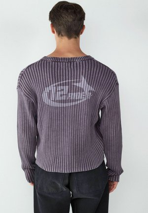 Lila gerippter Pullover mit langen Ärmeln, Rundhalsausschnitt und einem dezenten Logo-Druck auf der Rückseite. Weiche Textur und lockere Passform mit abgerundetem Saum.
