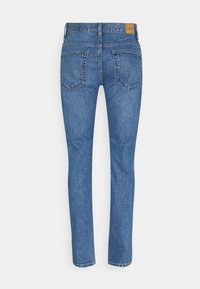 Vaqueros de mezclilla azul con diseño de pierna recta, con cintura de altura media, dos bolsillos traseros y una parche de cuero en la cintura.