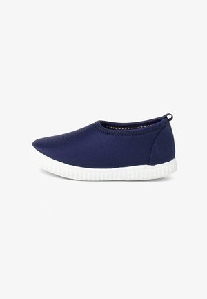 Námornické slip-on boty vyrobené z měkké tkaniny s bílou gumovou podrážkou. Vyznačují se zaoblenou špičkou a minimalistickým designem bez viditelných vzorů.