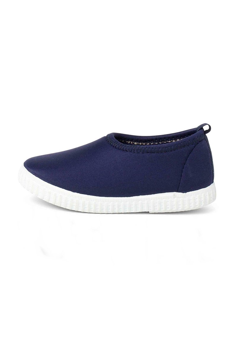 Zapatos slip-on de color marino hechos de una tela suave con una suela de goma blanca. Presentan una punta redondeada y un diseño minimalista sin patrones visibles.